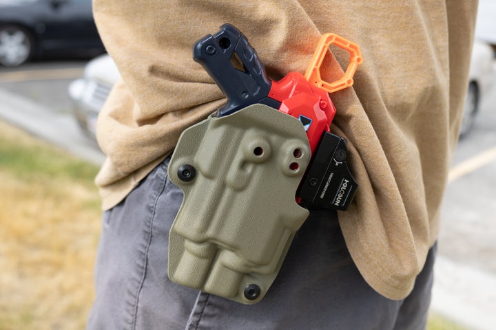 Person wearing a tactical pouch with tools on their back in an outdoor setting