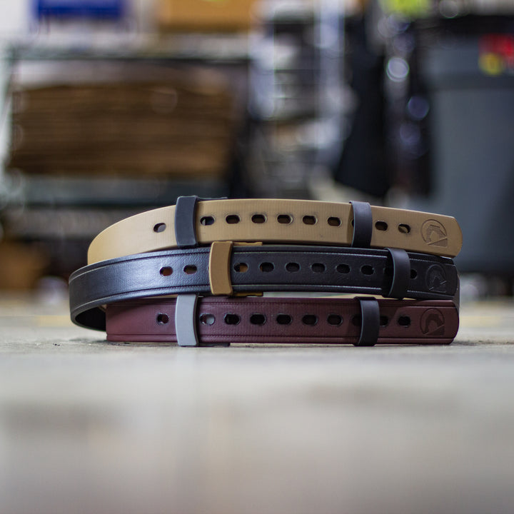 Three Black Arch EDC Belts stacked in tan, brown, and black, showcasing their durable polymer-coated material, customizable fit, and low-profile aluminum buckle—perfect for concealed carry and everyday carry setups.