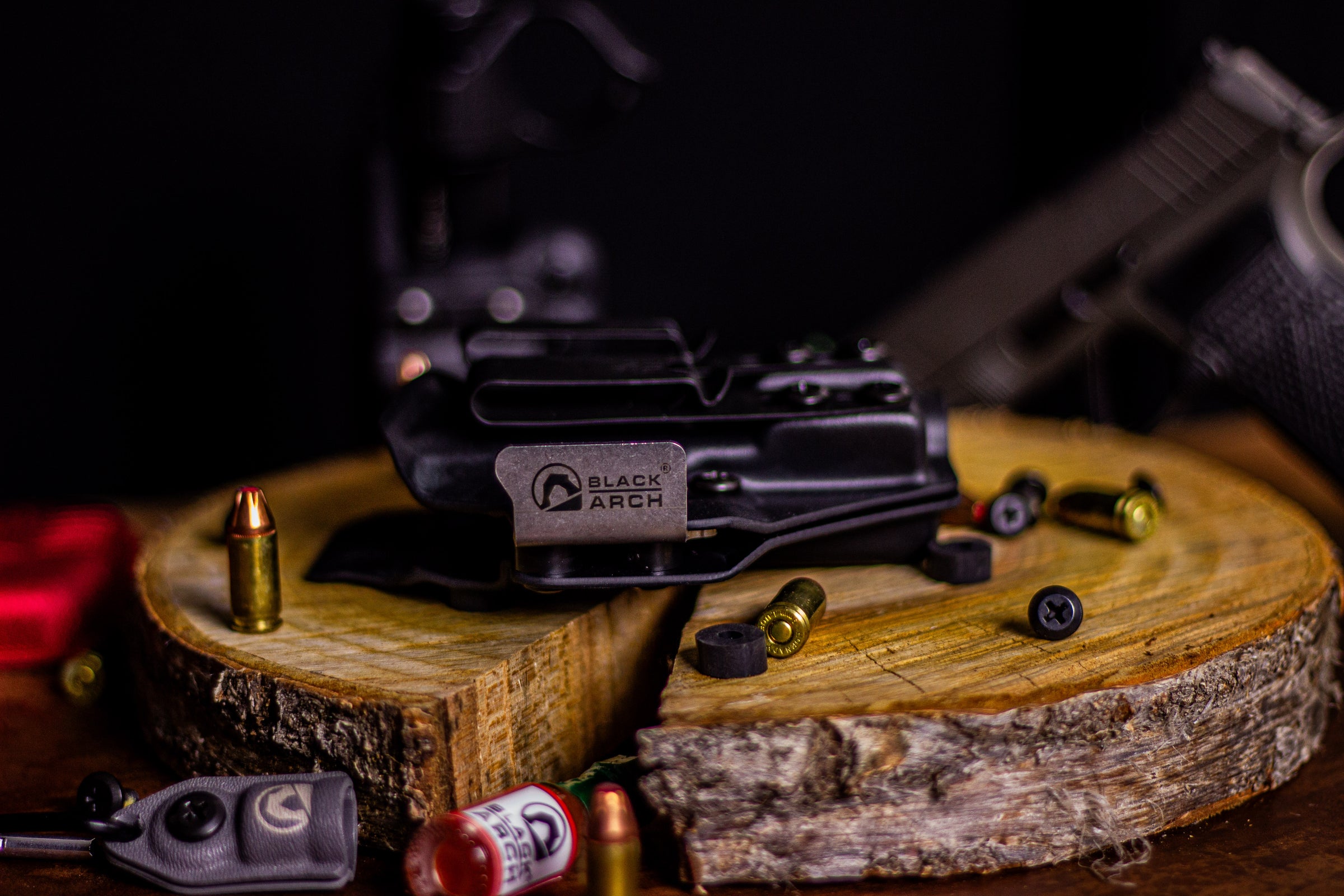 Right-hand Gradient Minimalist holster for Glock 19 shown on a wood slab with scattered rounds and accessories.